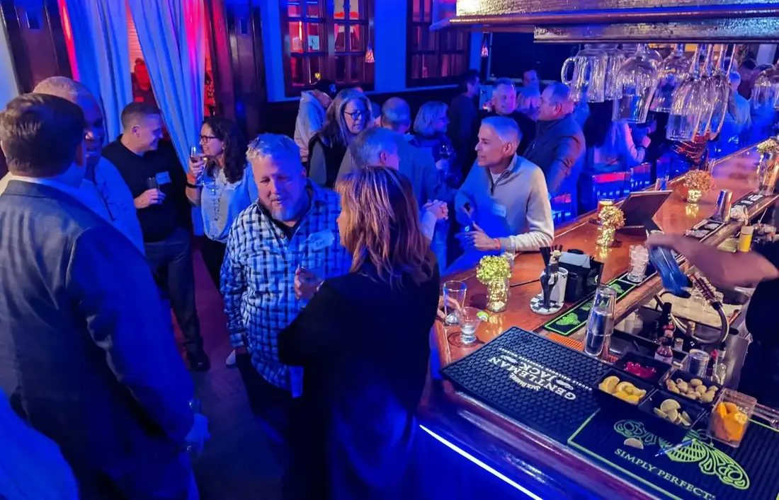 A busy bar at 660 LIVE, guests along the rail and bartenders working under blue lighting.