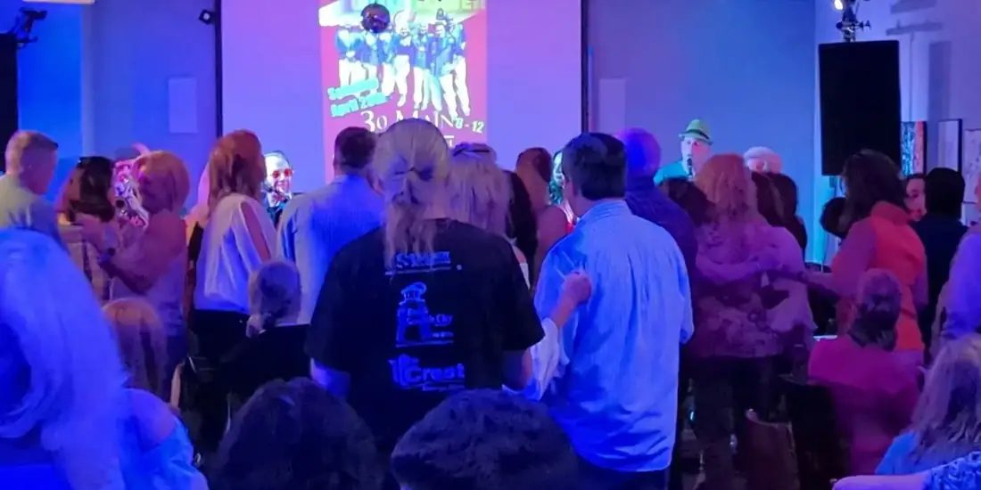 A packed dance floor at 660 LIVE, the room lit blue and purple with a band playing at the far end.