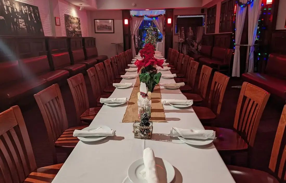 A long table set for a holiday party with white linen and poinsettias.