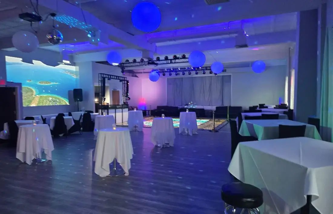 The Loft at 660 laid out with cocktail tables, hanging lanterns and blue uplighting ahead of an event.