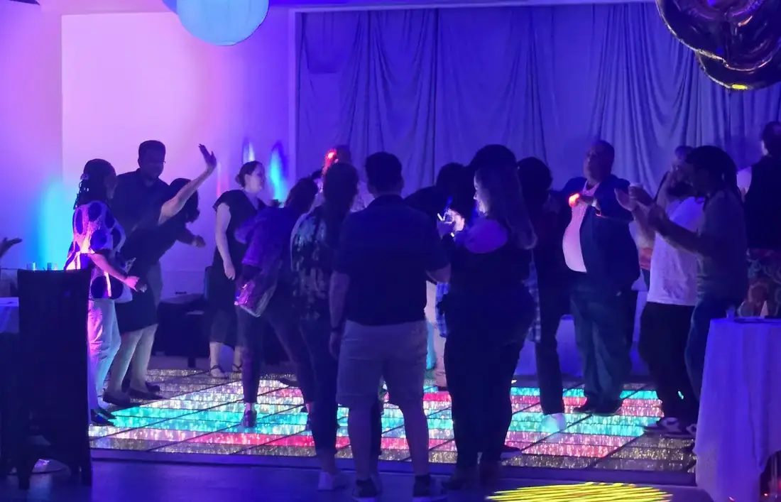 Guests dancing on the lit LED floor in The Loft at 660 under blue stage lighting.