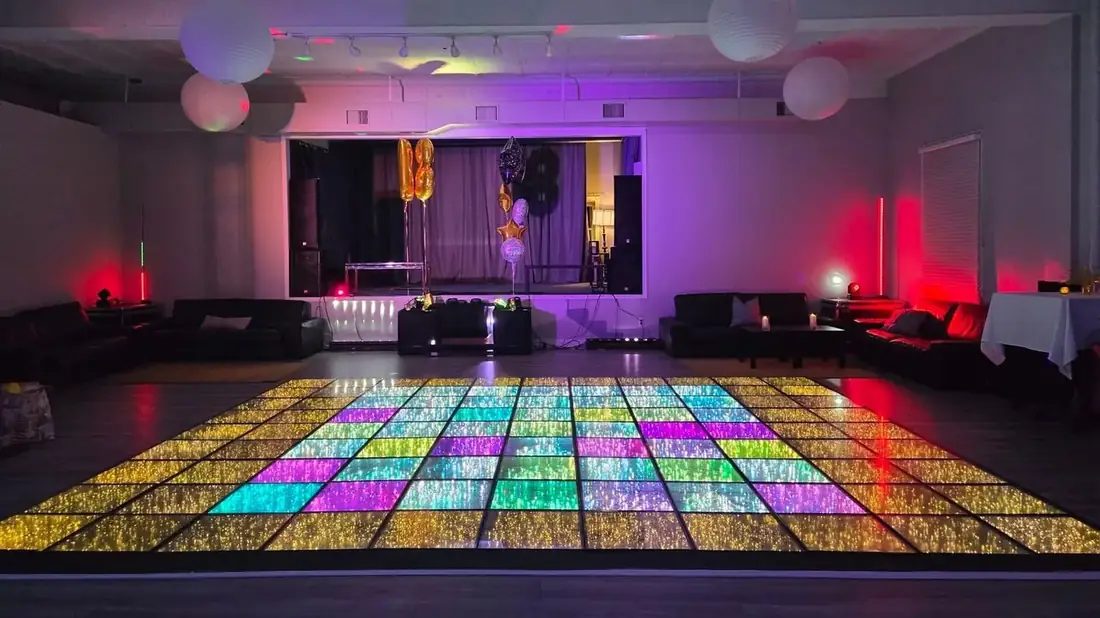 The Loft at 660 with the LED dance floor lit in rainbow colours, lounge seating around the edges and the stage at the far end.