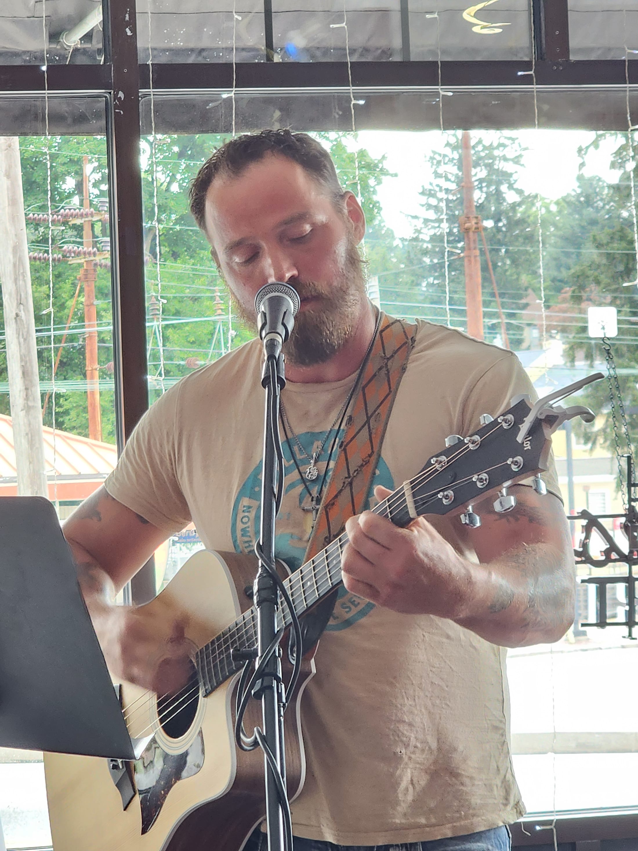 A solo performer singing into the microphone with an acoustic guitar at 660 LIVE