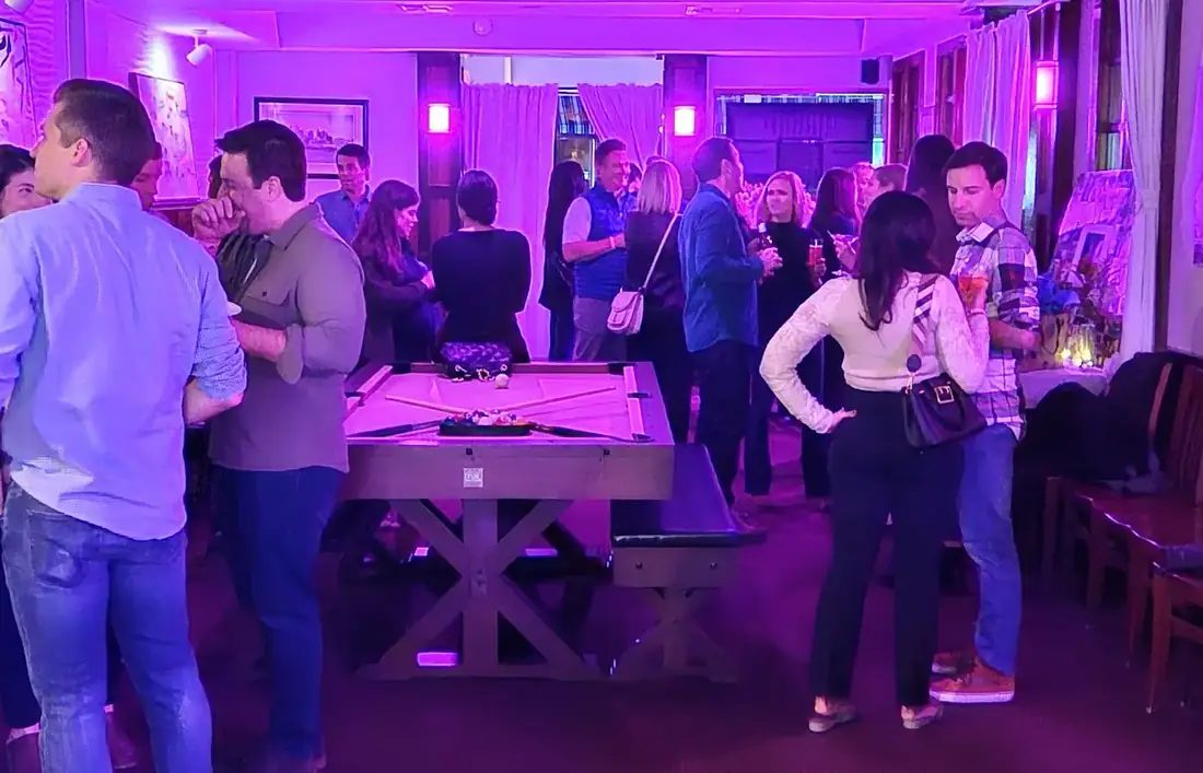 A crowd around the pool table in the front room at 660 LIVE during a party.