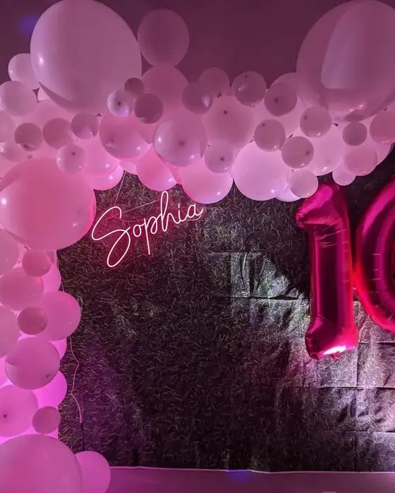 A pink and white balloon arch with a personalised neon name sign and giant number balloons set up for a sweet sixteen at 660 LIVE.