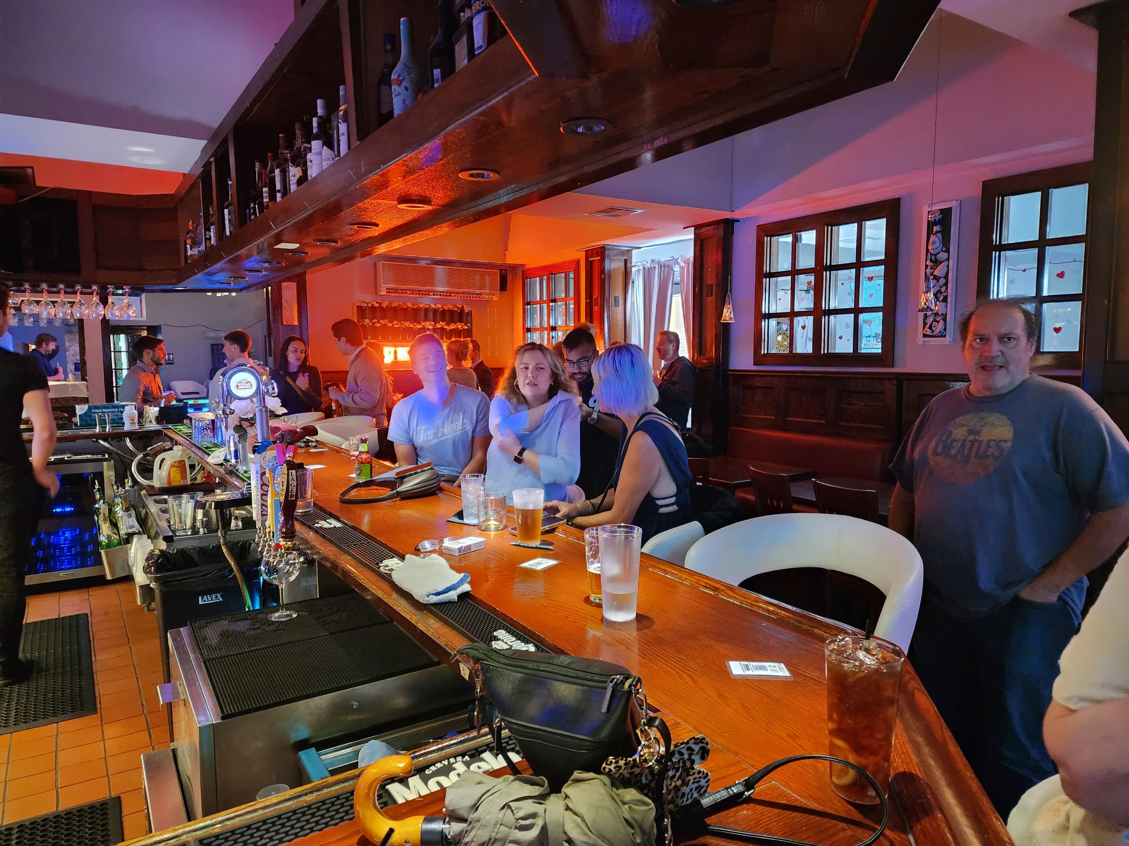 Guests at the wooden bar at 660 LIVE, taps and glassware along the counter under warm lighting